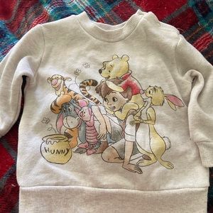 This charming sweater brings characters from the Winnie the Pooh series to life.